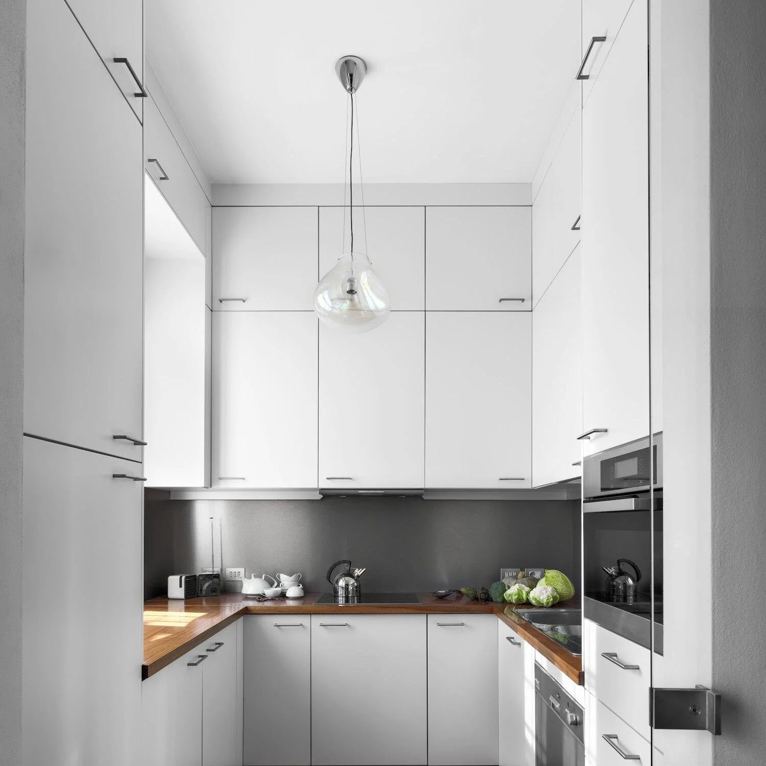 A freshly painted modern kitchen with sleek white cabinets.